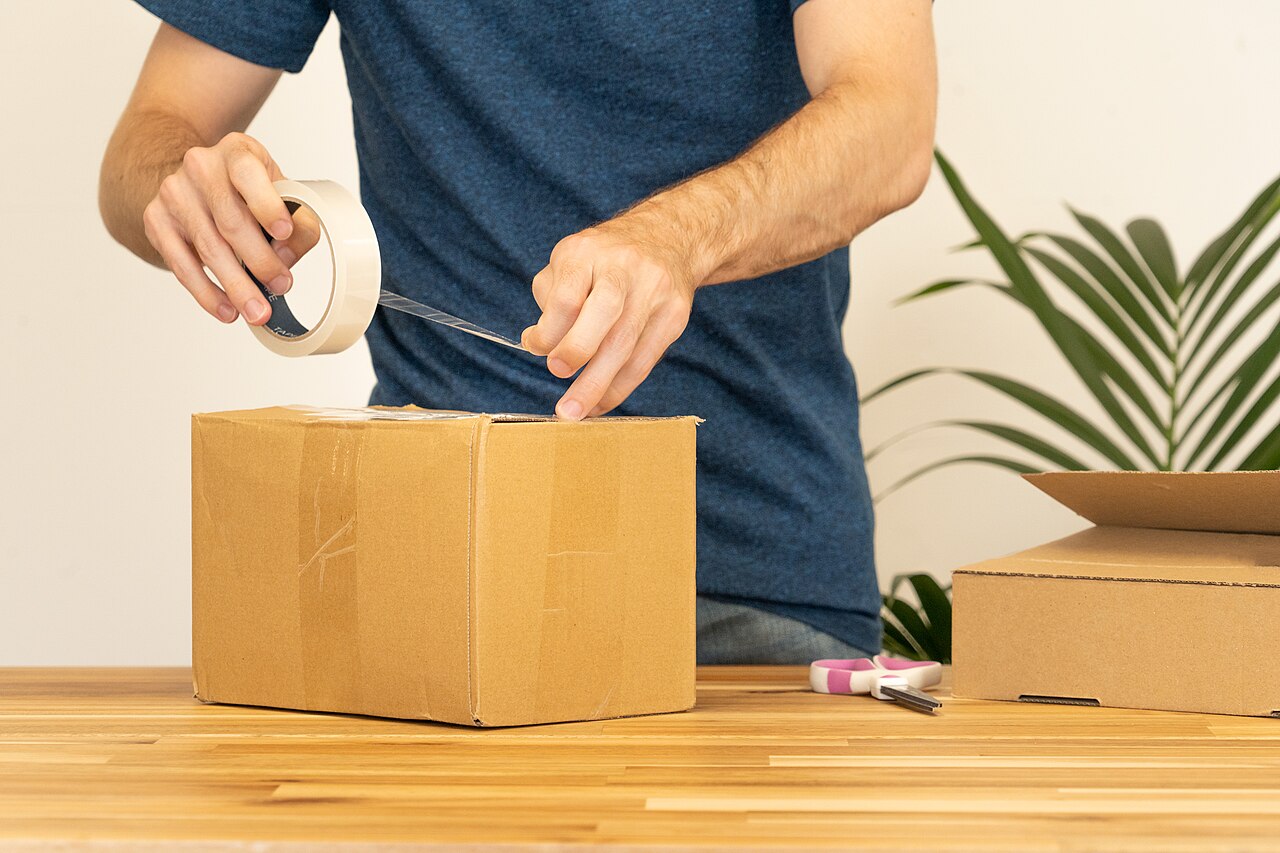 Ein Paket wird mit Klebeband verschlossen, bereit für den Versand